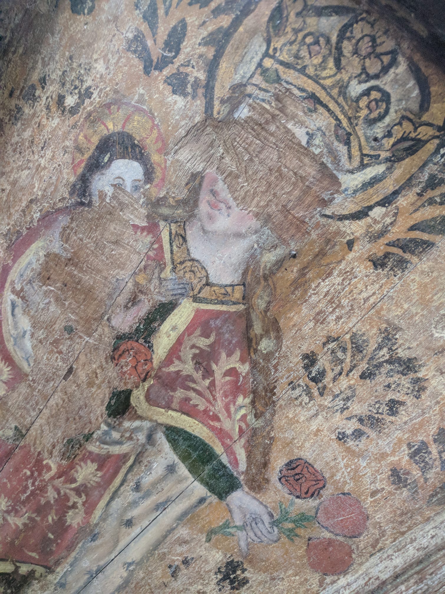 15th century rood screen painting of the Virgin Mary holding her son and a bunch of roses; her face has been scratched off.