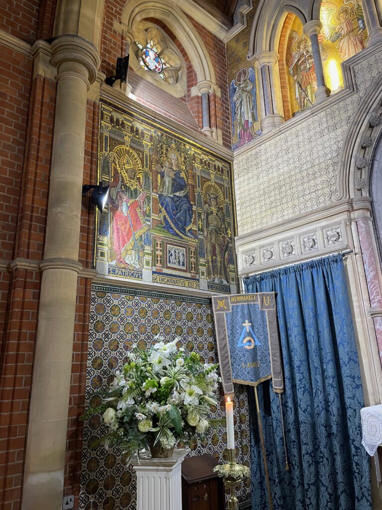 A corner next to the altar in St Agnes chapel, Newmarket, tilings, brickwork, cinquefoil window in an arch, angel mosaices, relief sculptures, pillar
