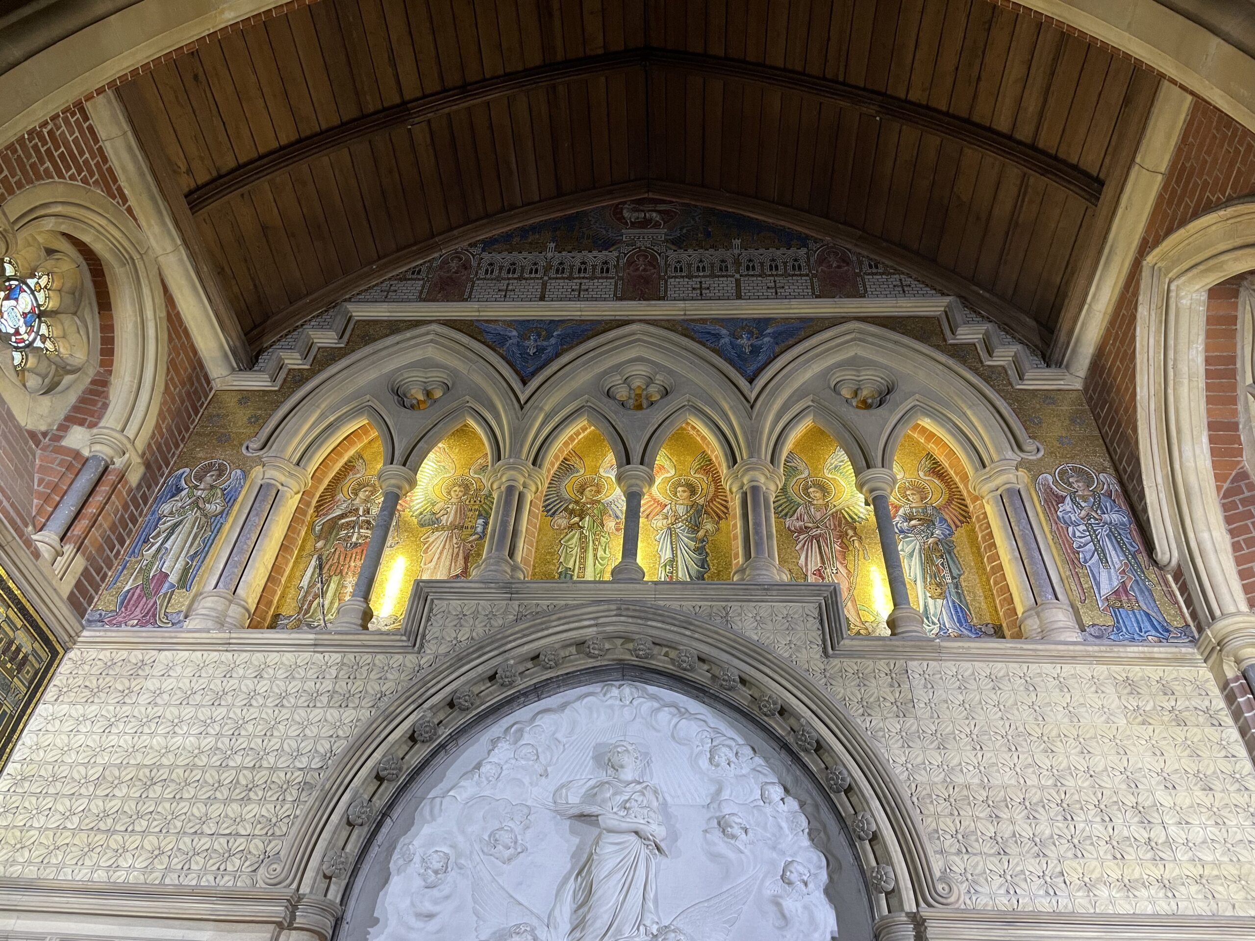 Above the altar in St Agnes Newmarket, Relief Sculpture in white of Vrigin Mary plus 3 arched portals and rich mosaics of angels